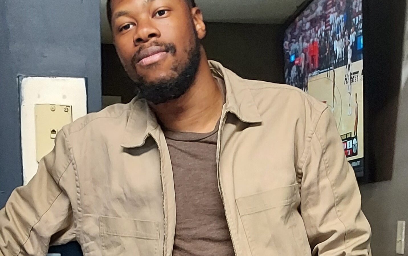 Picture of artist Jon-Keith Gary wearing a light tan jacket and a light brown shirt.