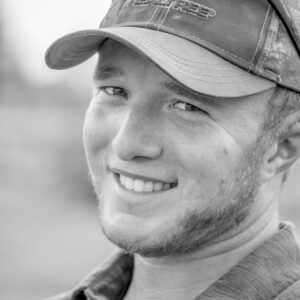 Person with short hair under a baseball cap smiling