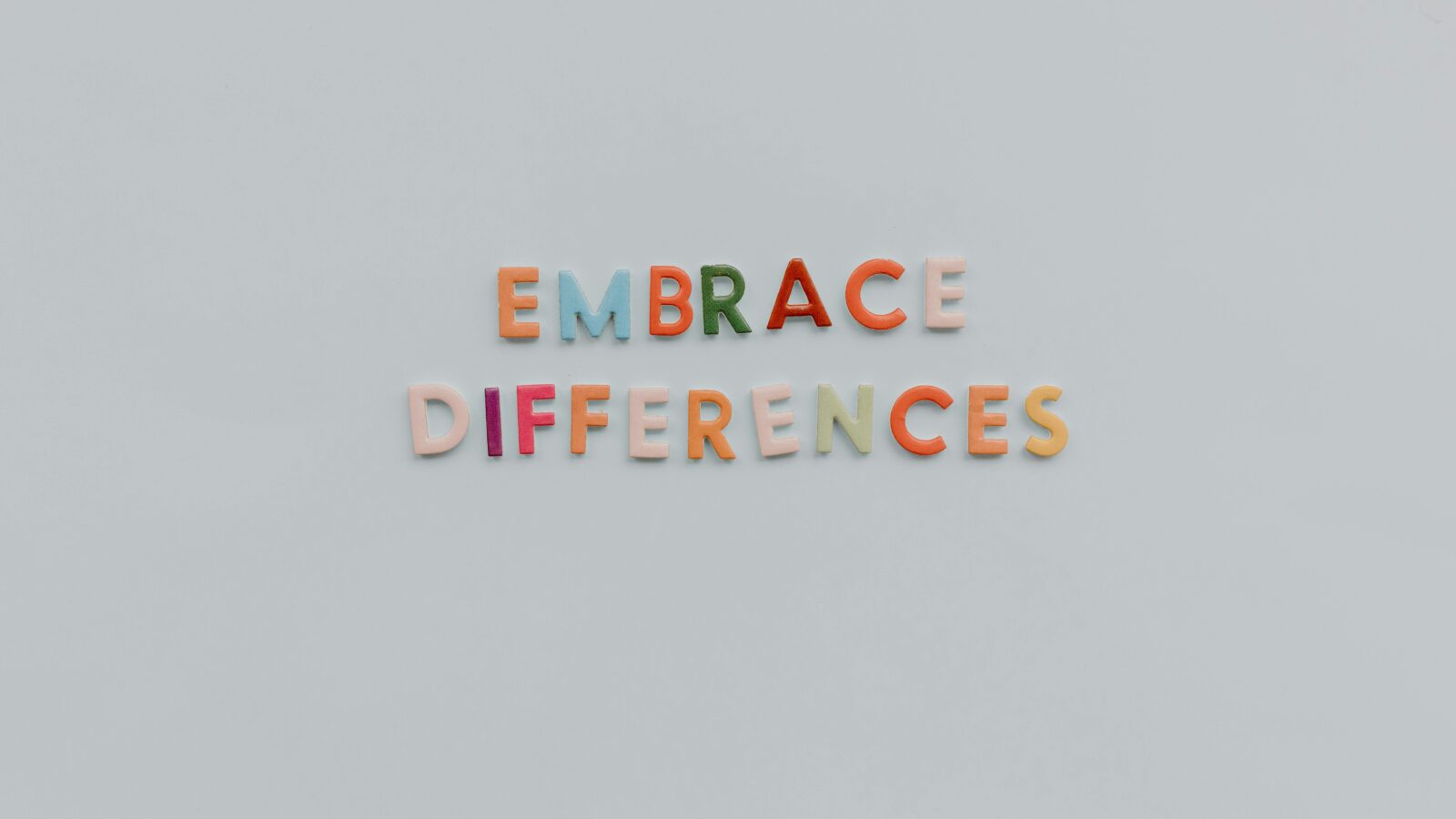 rainbow letter blocks that spell out "embrace differences" on a grey background