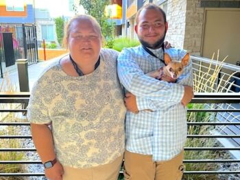 Rebecca has arm around her adult autistic son Austin as they smile standing on an outdoor patio