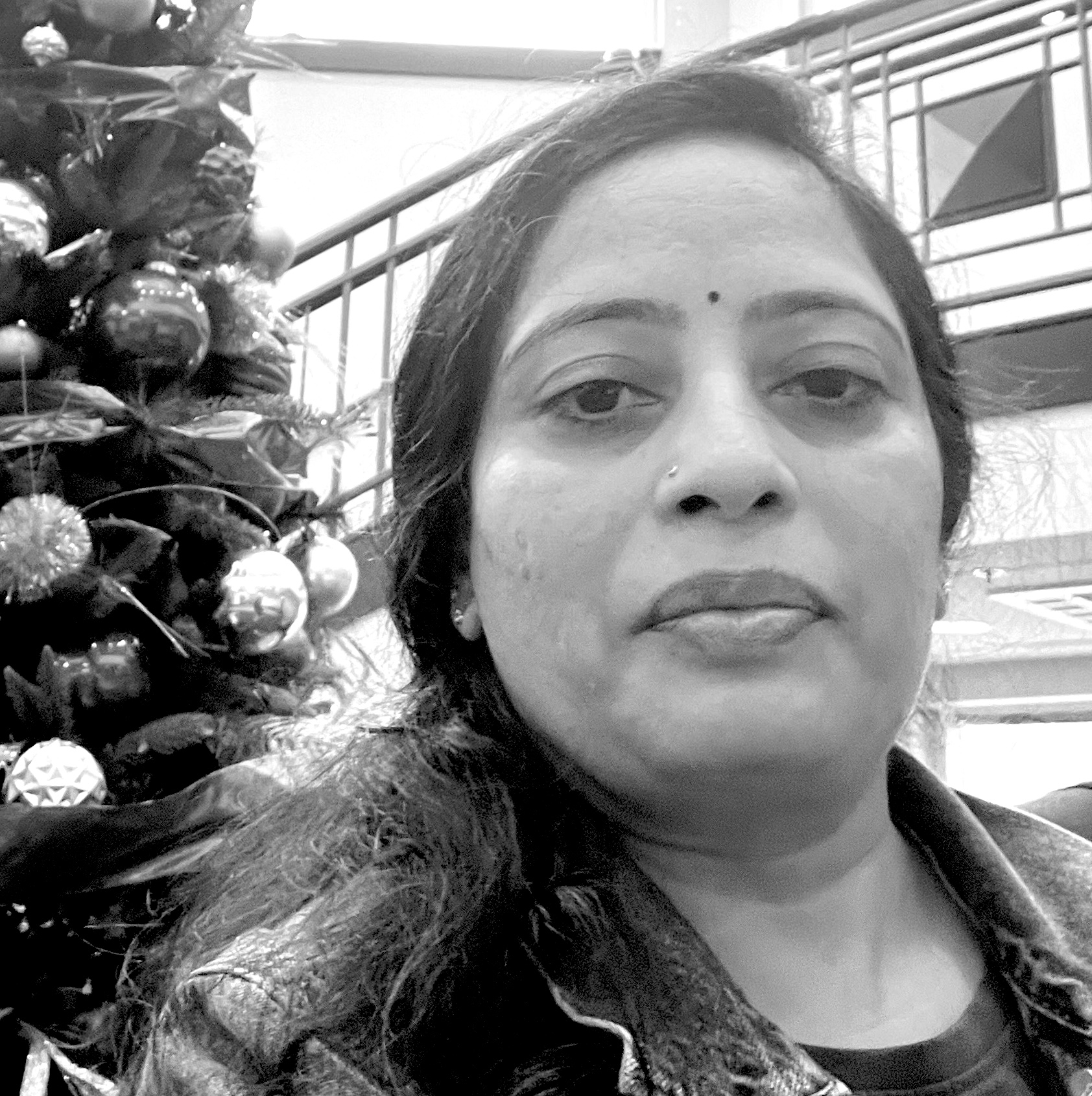 Woman looking at camera with a holiday tree behind her