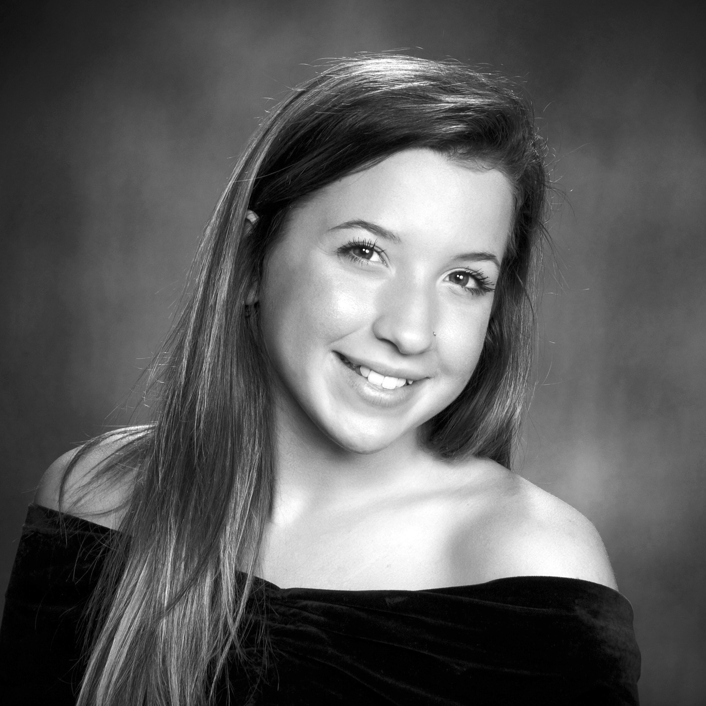 Young adult with long, dark hair smiles at the camera