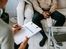 Person sitting on couch facing someone with a clipboard.